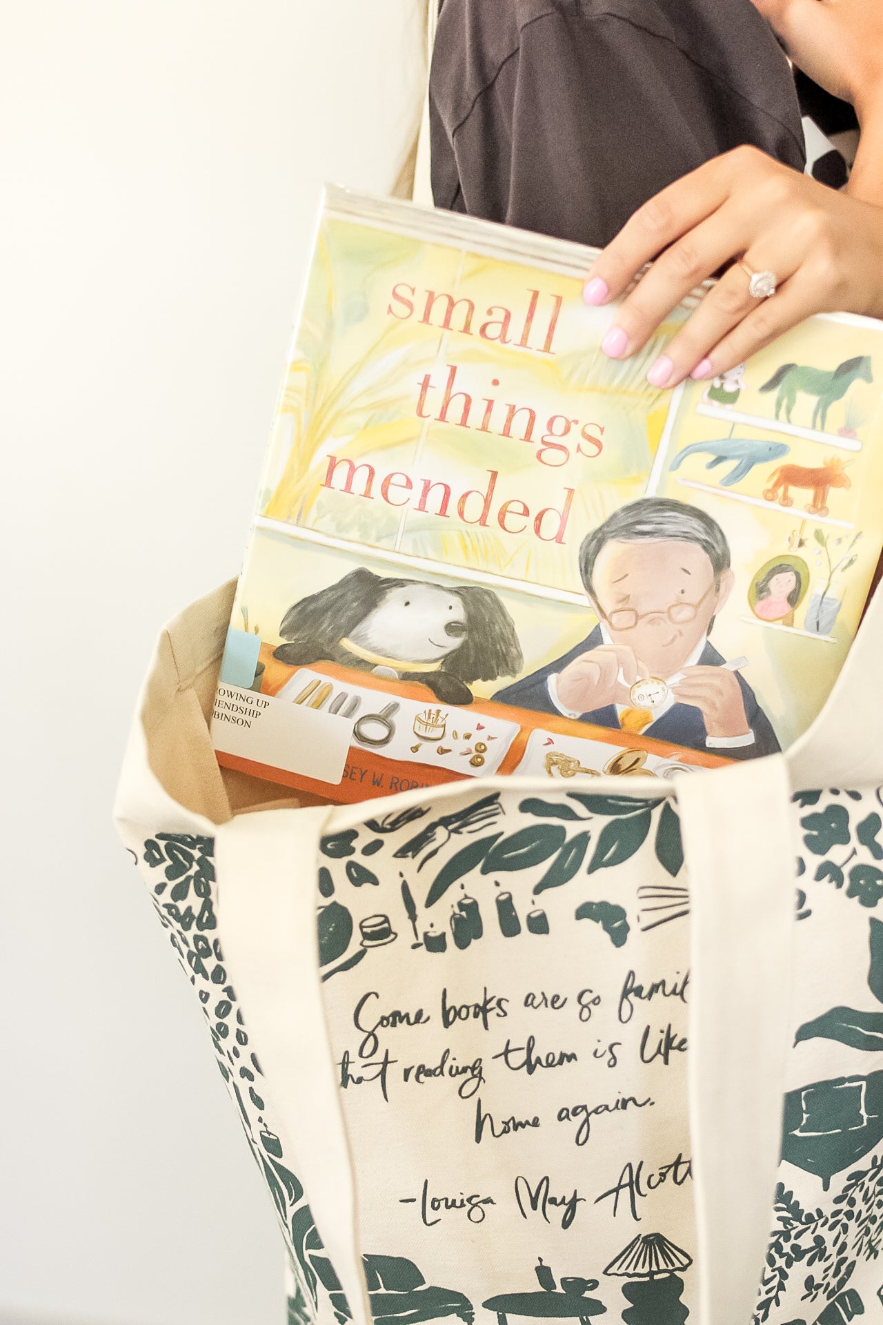 Children's book being placed into a blue patterned tote bag.