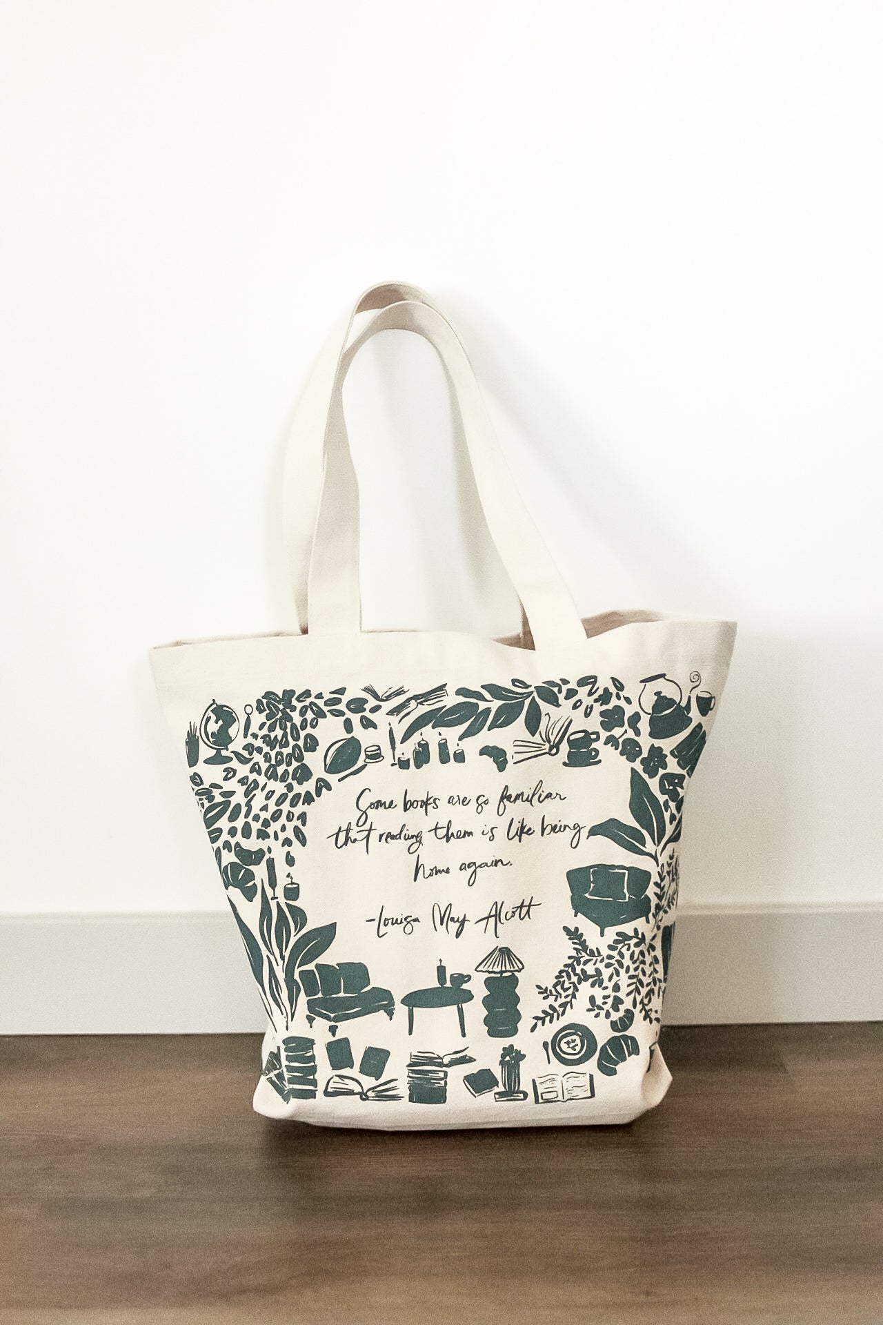 Tote bag with floral and book-themed design on a wooden surface